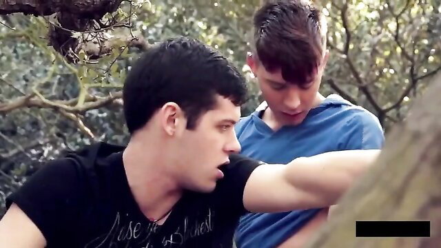 Two fit young guys in outdoor woods hookup, one reaching from behind