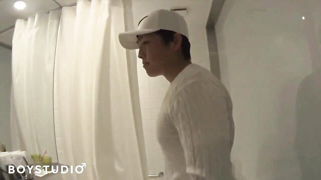Handsome Asian man in white sweater and cap, side profile in bedroom