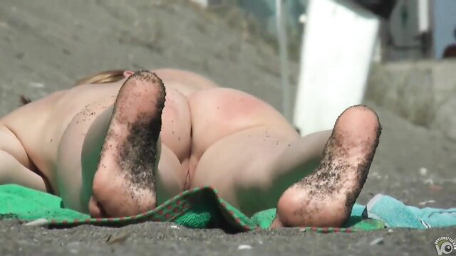 Nude blonde amateur sunbathing on beach, sandy feet and bare ass up