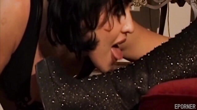 Two hot brunettes in lesbian tongue kiss, one in sparkly black boots
