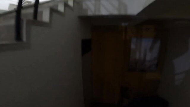 Dark indoor stairwell with railing and open door, dimly lit
