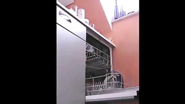 Amateur housewife putting dishes away in kitchen, bending over dishwasher