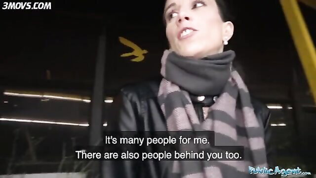Brunette in leather jacket and scarf nervous at crowded night station