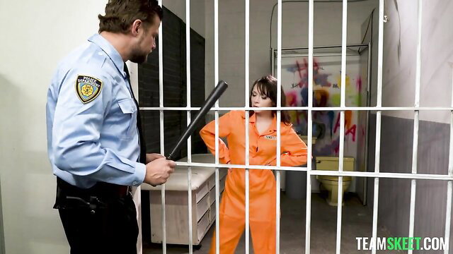 Ava Sinclaire in orange prison jumpsuit cuffed by cop behind bars