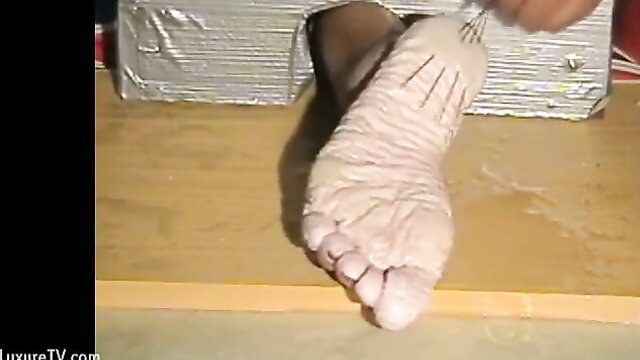 Closeup of pale wrinkled wet sole tortured with pins in BDSM foot sawing