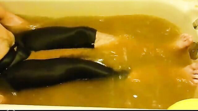 Woman pooping in tight black lycra pants in yellow-filled bathtub
