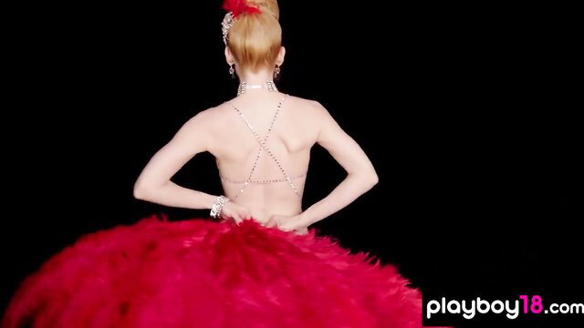 Blonde burlesque babe in red feathered dress back view