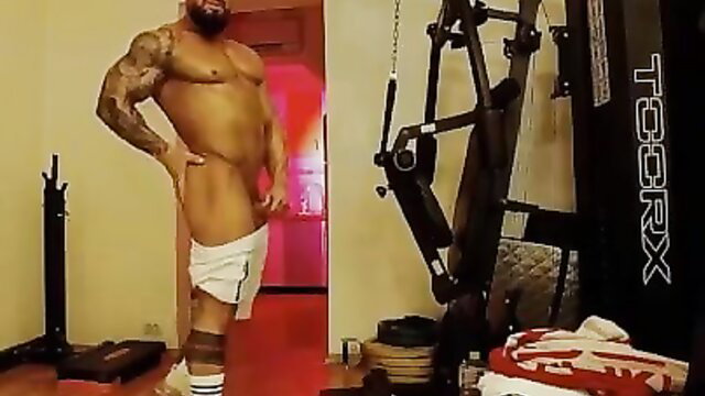 Tattooed muscular Latino hunk posing nude in tight white shorts