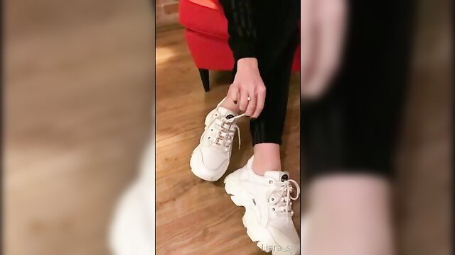 Asian amateur sits legs spread in black leggings and white chunky sneakers