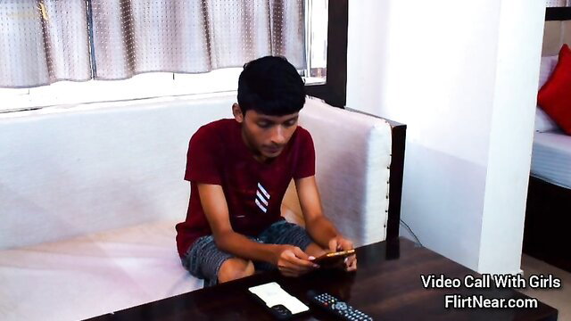 Young Indian guy video calling girls on phone in hotel room