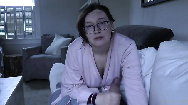 Bettie Bondage in pink robe, glasses, thumbs up on couch