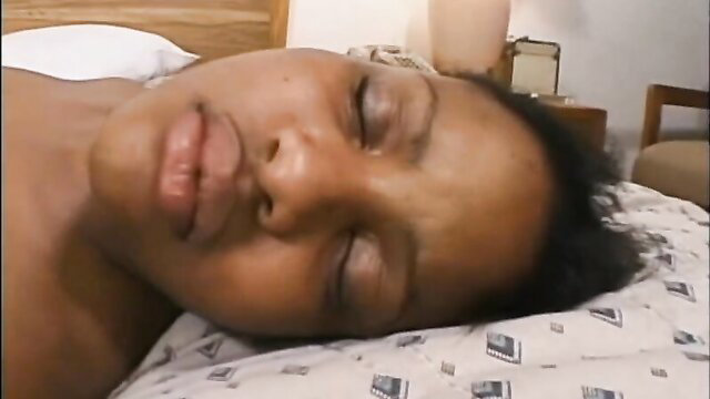 Charming black seductress lying nude asleep on bed closeup