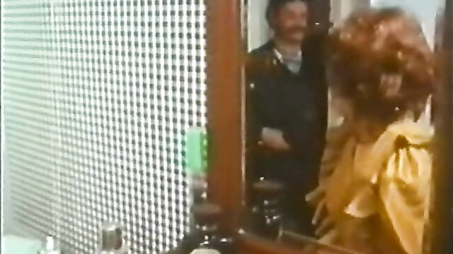 Vintage 1976 porn: brunette in yellow dress with mustached man at mirror