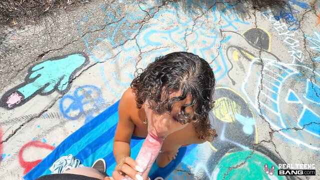 Curly teen Isabella Jules sucks pink dildo POV on graffiti ground