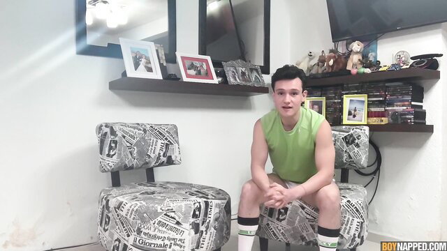 Handsome fit young amateur sits smiling in green tank top and socks