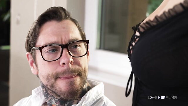 Tattooed bearded guy in glasses eyes busty woman's black lace lingerie cleavage