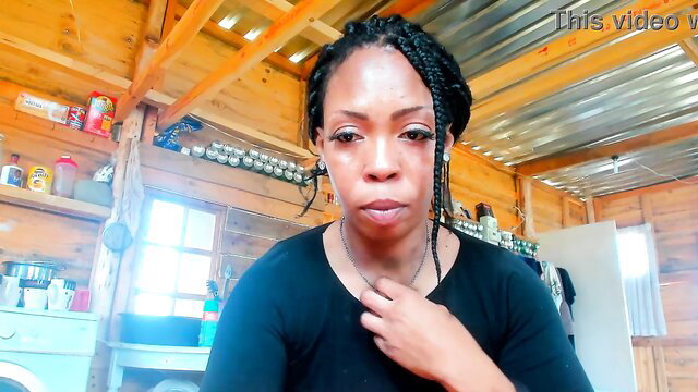Thick black woman with braids in black top, sultry face in kitchen
