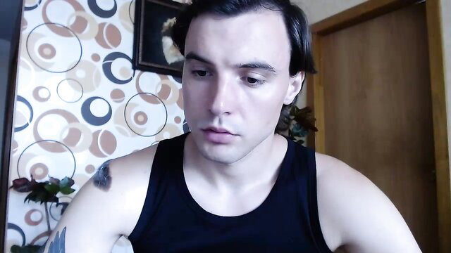 Young slim white guy in tank top with butterfly tattoo, intense gaze