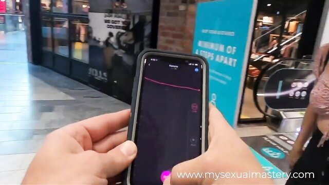 Girl holds phone controlling remote vibrator in mall, public tease