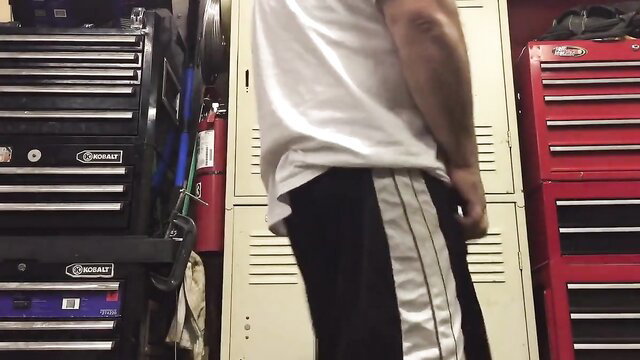 Muscular man in track pants with huge balls bulge in garage