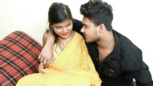 Indian wife in yellow saree cuddles husband on couch