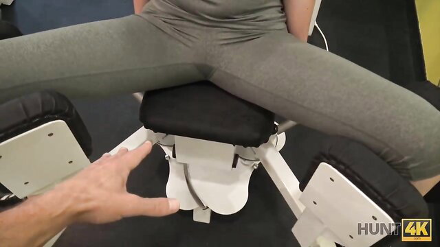 Gym girl in gray leggings spread wide on sex chair, hand teasing pussy