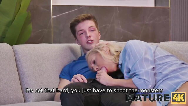 Blonde mature cougar hugs gamer guy on couch in teasing HD thumbnail