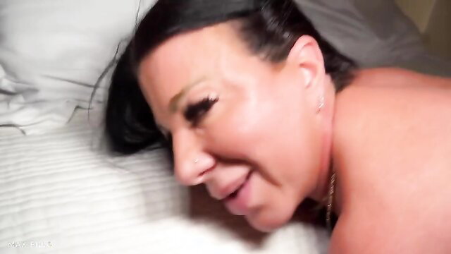 Hot MILF with black hair lying nude on bed smiling seductively