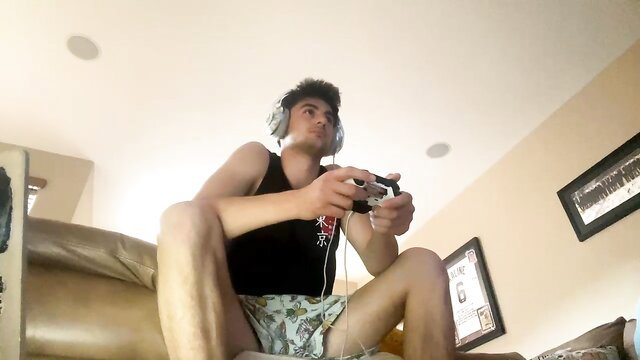 Hot college guy with black hair gaming in tank top and shorts
