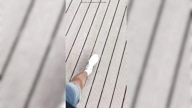 POV closeup of woman's smooth leg in white sneakers on wooden dock
