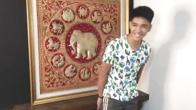 Smiling Filipino male model in floral shirt posing by Thai zodiac art