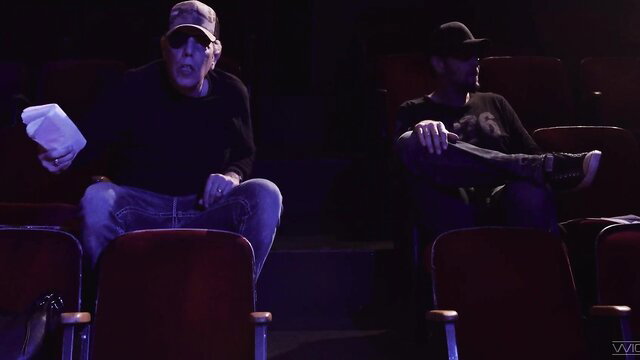 Seth Gamble holds popcorn with friend in theater seats