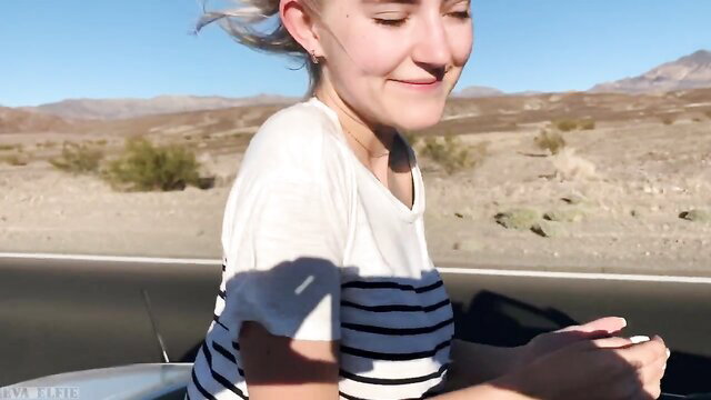 Eva Elfie smiles in car on Vegas desert road, striped top tease