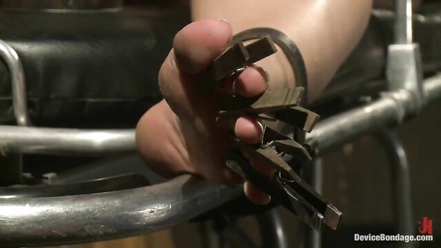 Asian foot domme holding metal clamps and keys in BDSM restraint scene