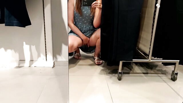 Busty Asian babe squats in polka dot dress in fitting room mirror selfie