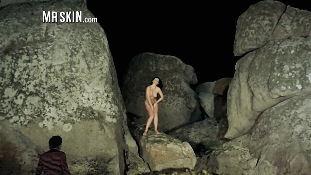 Nude Asian woman posing seductively outdoors among rocks at night