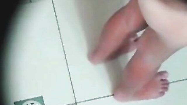 Hidden cam closeup of young woman's bare feet and legs in shower