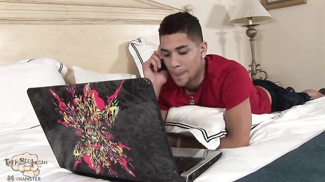 Latino twink in red shirt on bed with laptop, phone call tease