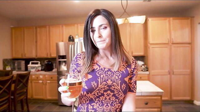 Helena Price holds beer in tight purple dress in kitchen