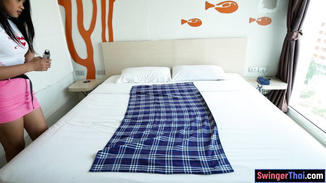 Thai teen girlfriend in red top pink skirt holding remote in hotel room