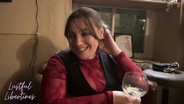 Lustful Libertines smiles seductively with wine glass in red top