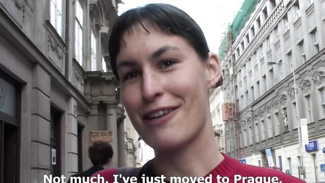 Julie smiles in red sweater on Prague street, public WC tease