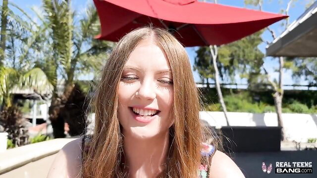 Zoey Zimmer smiling teasingly by pool in colorful top