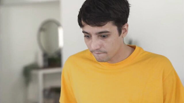 Handsome young man in yellow hoodie looking thoughtful