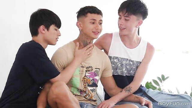 Three young Latino guys sharing hotel room, touching intimately