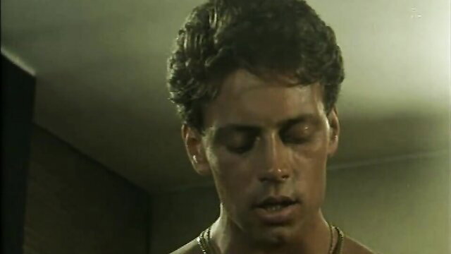 Handsome young man with curly hair and gold chain in lesbian porn scene