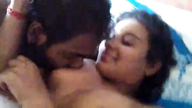 Passionate Sri Lankan couple in intimate embrace, man kissing woman's bare breast