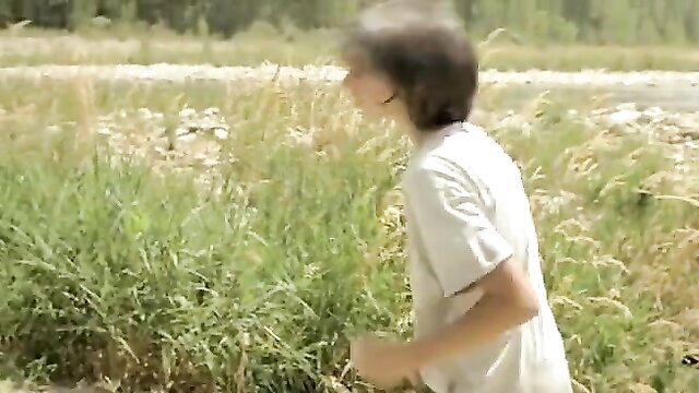 Young man running in field wearing white t-shirt, outdoor scene
