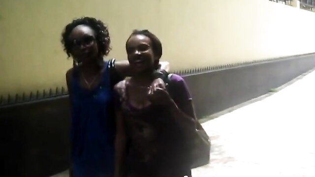 Two smiling black hotties embracing outdoors in tight tops