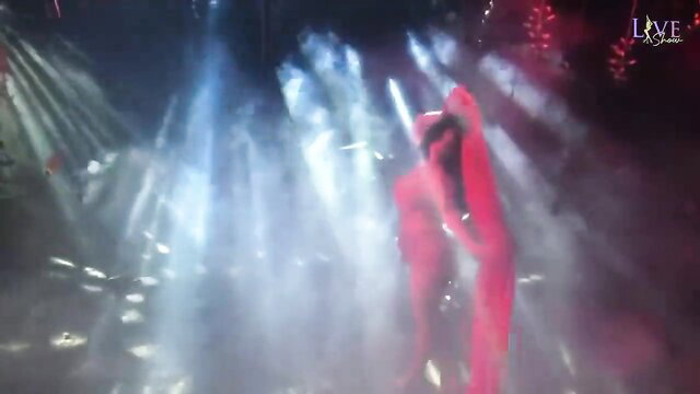 Sexy brunette in red dress dances seductively on Viva Max live show stage